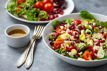 Healthy salad with tomatoes, feta, pomegranate seeds and leek.