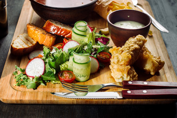 Lunch on a wooden board. Soup, chicken breast, salad and sauce.