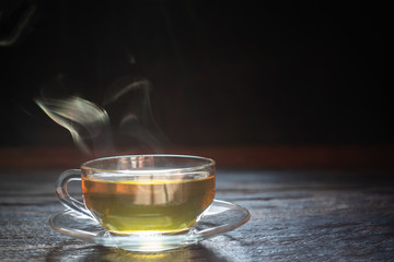 Hot tea cup with steam on wood background