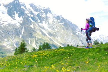 Woman hiking in mountain range. Rear view of a female backpacker walking on a small foot path in a mountain landscape. Image for trekking, hiking or climbing.