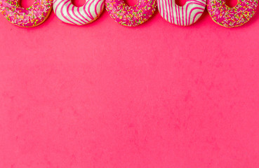 Row of half donut on pimk background. Photo of sweets with copyspace. Top view.
