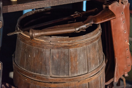 Old muzzleloader pistol standing on an antique wooden barrel