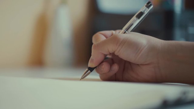 A male hands writing on a piece of paper. Writing essay or letters. Doing homework.