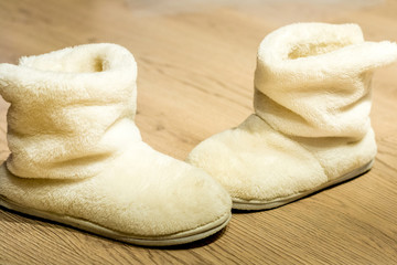 Fluffy white warm boots on a beautiful home floor.