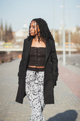 Young woman dressed in casual clothes walking on the street, soft focus background