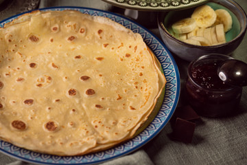 Cooked crepes folded on a plate with jam and apples