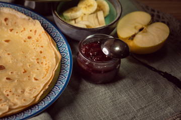 Cooked crepes folded on a plate with jam and apples