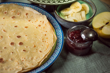 Cooked crepes folded on a plate with jam and apples