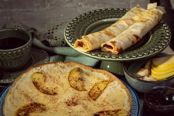 Cooked crepes folded on a plate with jam and apples