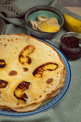 Cooked crepes folded on a plate with jam and apples