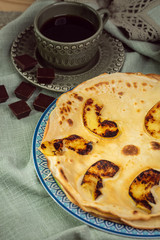 Cooked crepes folded on a plate with jam and apples