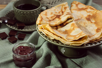 Cooked crepes folded on a plate with jam and apples