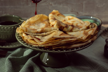 Cooked crepes folded on a plate with jam and apples