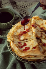 Cooked crepes folded on a plate with jam and apples