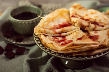Cooked crepes folded on a plate with jam and apples
