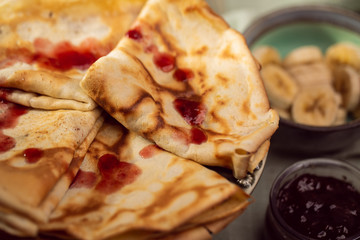 Cooked crepes folded on a plate with jam and apples