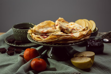 Cooked crepes folded on a plate with jam and apples