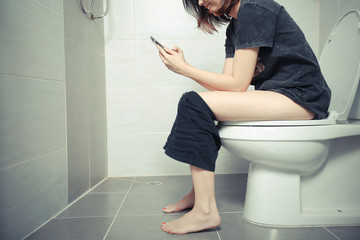Woman using a smartphone on toilet in morning.
