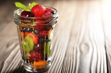 Assorted berries in mason jar on kitchen wooden table