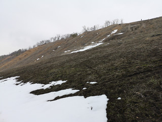 Russian landscape with hills in the melting forest in early spring