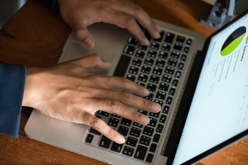 Close up Asian business man using laptop for working in coffee shop in selective focus.