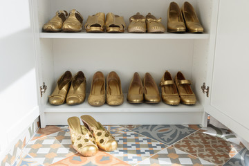 Old fashionable women shoes painted with gold paint. Capsule wardrobe, order in the closet, shoes compiled neatly. Concept. Cleaning. Wardrobe order. Cloak study. Footwear.