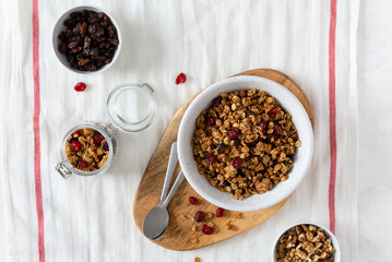 Bowl of homemade granola with nuts and fruits on white linen background. Top view, copy space