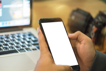 Close up hand of asian young freelance using laptop and smartphone for working with his job in coffee shop at the night.