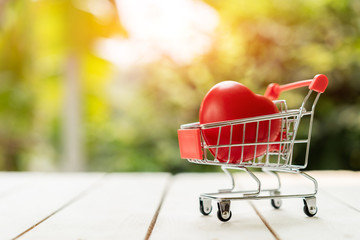 Red heart in the shopping cart on the wood. Love shopping concept