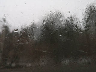 Texture of dripping drops on window closeup in spring in March