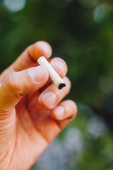 cigarette extinguished in his hand a man with a beard on nature against the background of green...