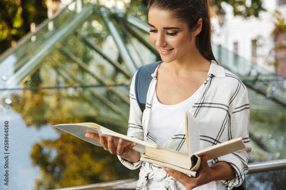 Wall mural Pretty girl student reading a book