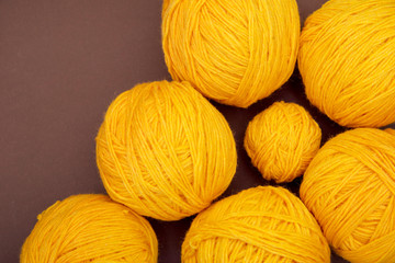Yellow Balls of yarn for knitting on the brown background