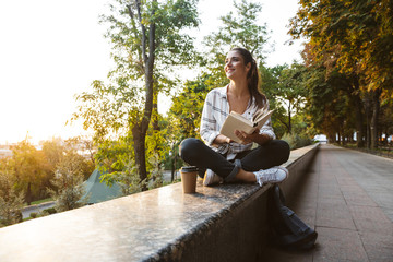 Fototapeta premium Lovely young student girl sitting outdoors