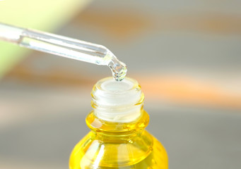 Dropping serum collagen moisturizer of face into clear yellow bottle soft light background. Protector skin Treatment facial essence oil, Vitamin C. Beauty and spa Concept.