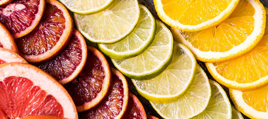 Flat lay slices of different raw fresh citrus fruit.