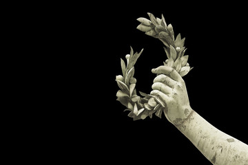 Hand holds a laurel wreath - bronze statue on black background - Success and fame concept image -...