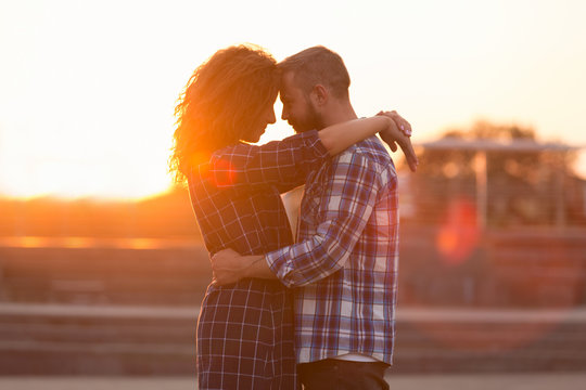 Beloved couple embracing and touching their foreheads at sunset