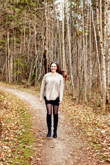 Porträt einer jungen Frau mit langen Haaren stehend im herbstlichen Wald 