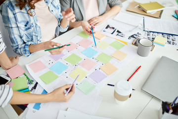 High angle closeup of creative business team planning project placing colorful stickers on roadmap,...