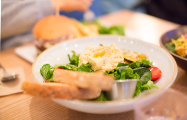 Healthy Vegetable Salad of Fresh Tomato, Lettuce, Hummus, Squash, and Bread on Plate. Diet Menu. Homemade Salad in a Plate for Vegetarian Diet. Vegan Food Providing Vitamin Snack.