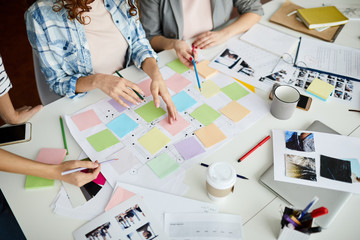 High angle closeup of contemporary business team planning project placing colorful stickers on...
