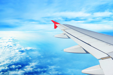 The plane flies in the afternoon over a beautiful blue sky in the afternoon: a white wing flies through the day sky, beautiful clouds