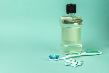 Oral rinse, gum and dental floss on green background. 