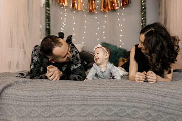 Young mom and dad rejoice at the smile of their daughter