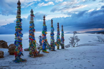 Wooden ritual pillars with colorful ribbons on cape Burkhan in sunrise, Lake Baikal, Olkhon, Russia
