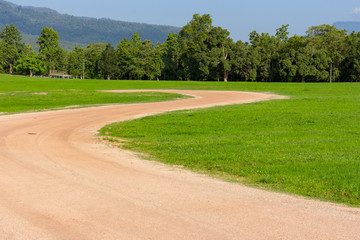 Brown road cut on the green field.