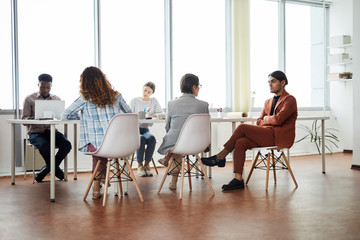 Multi-ethnic group of contemporary business people working at table in office, copy space