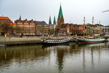 Fototapeta premium Alexander von Humboldt tall ship and others wooden sailing ships and barg floating on the banks of the River Weser. St. Martini church on the background. Bremen, Germany. March 2019