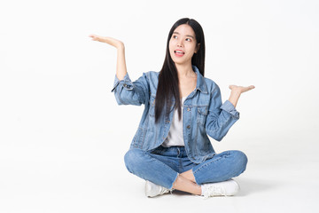 Thinking asian woman sitting on floor isolated on white background.Asian female model smiling looking up.woman pointing fingers away while sitting on a floor with legs crossed isolated